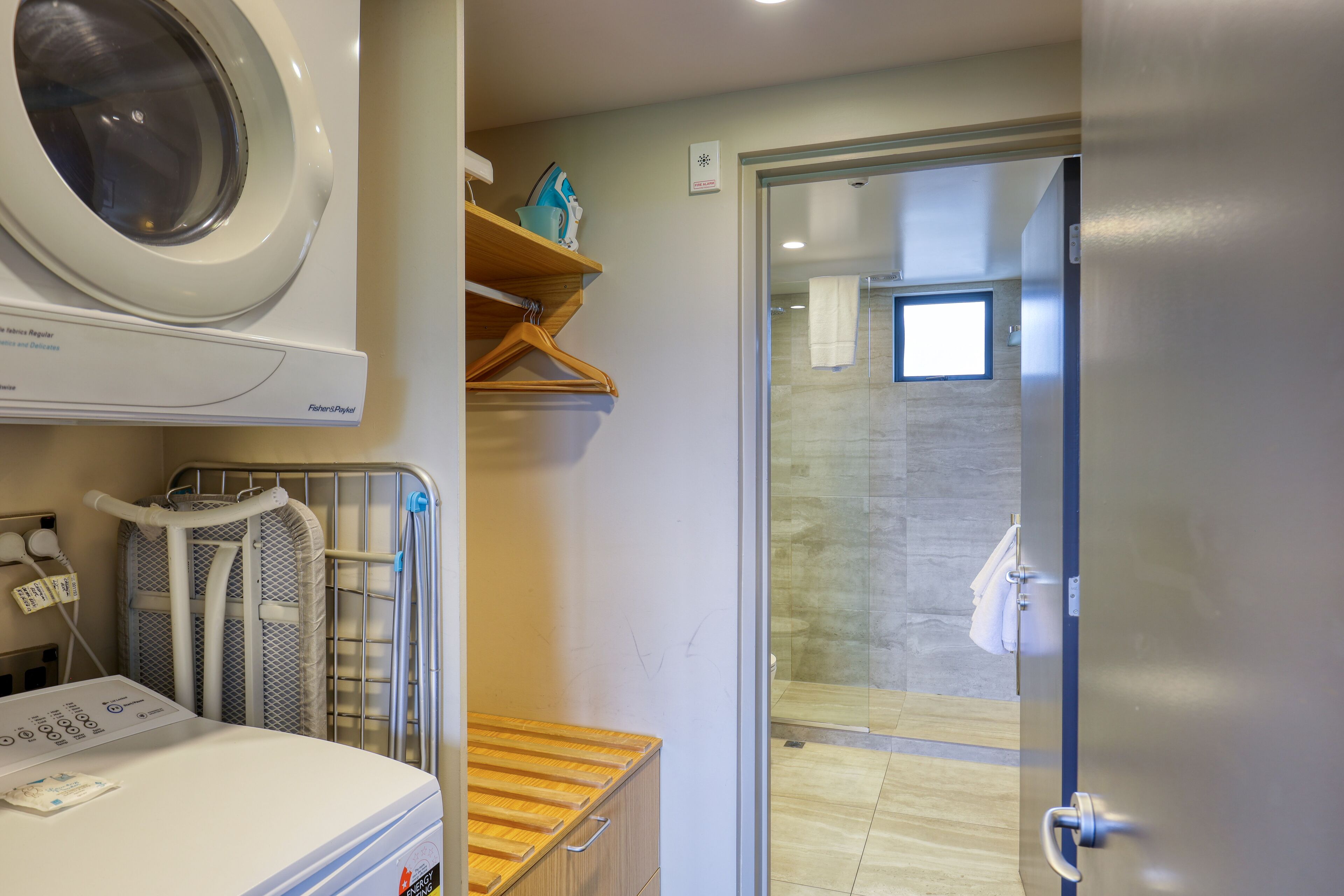 A laundry area with a washing machine, drying rack, and ironing station.