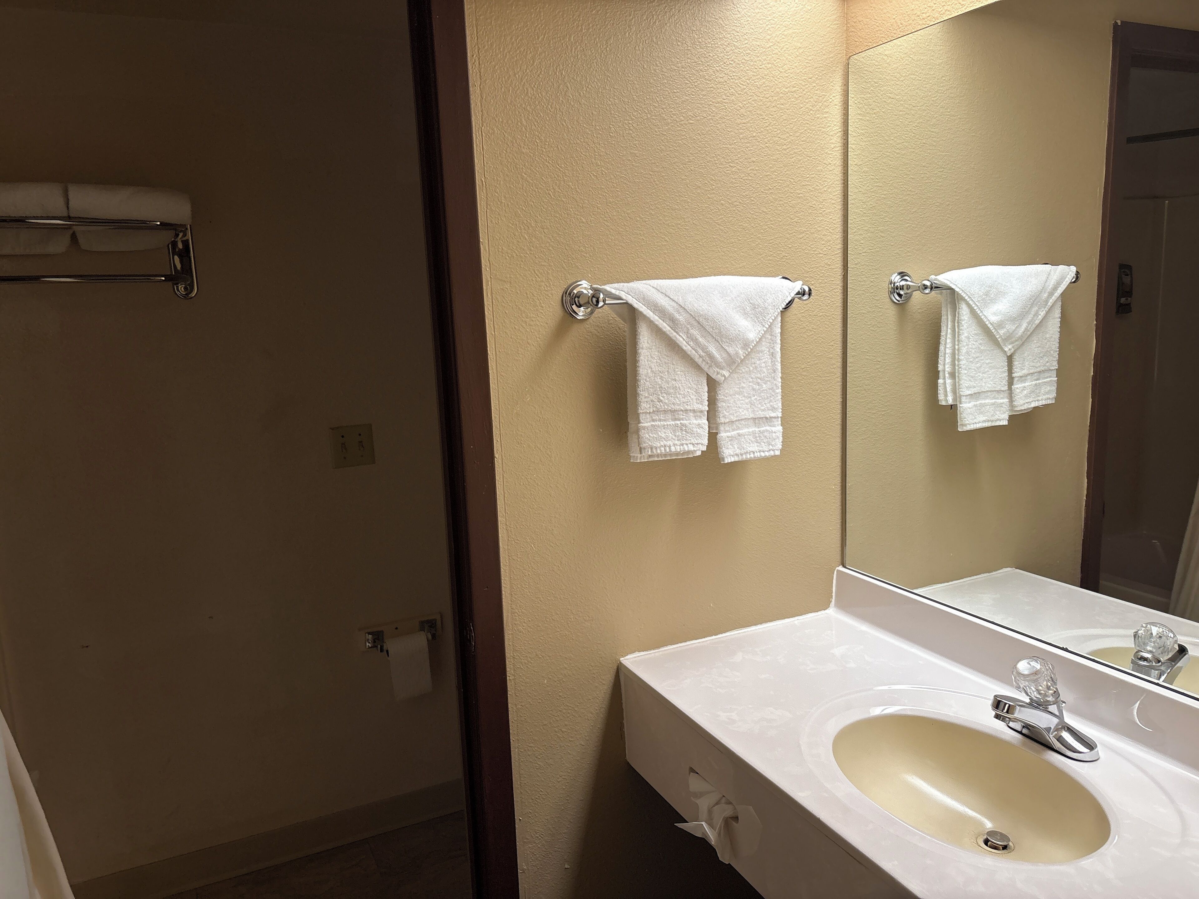 A bathroom with a sink, mirror, and two towels hanging on towel bars.