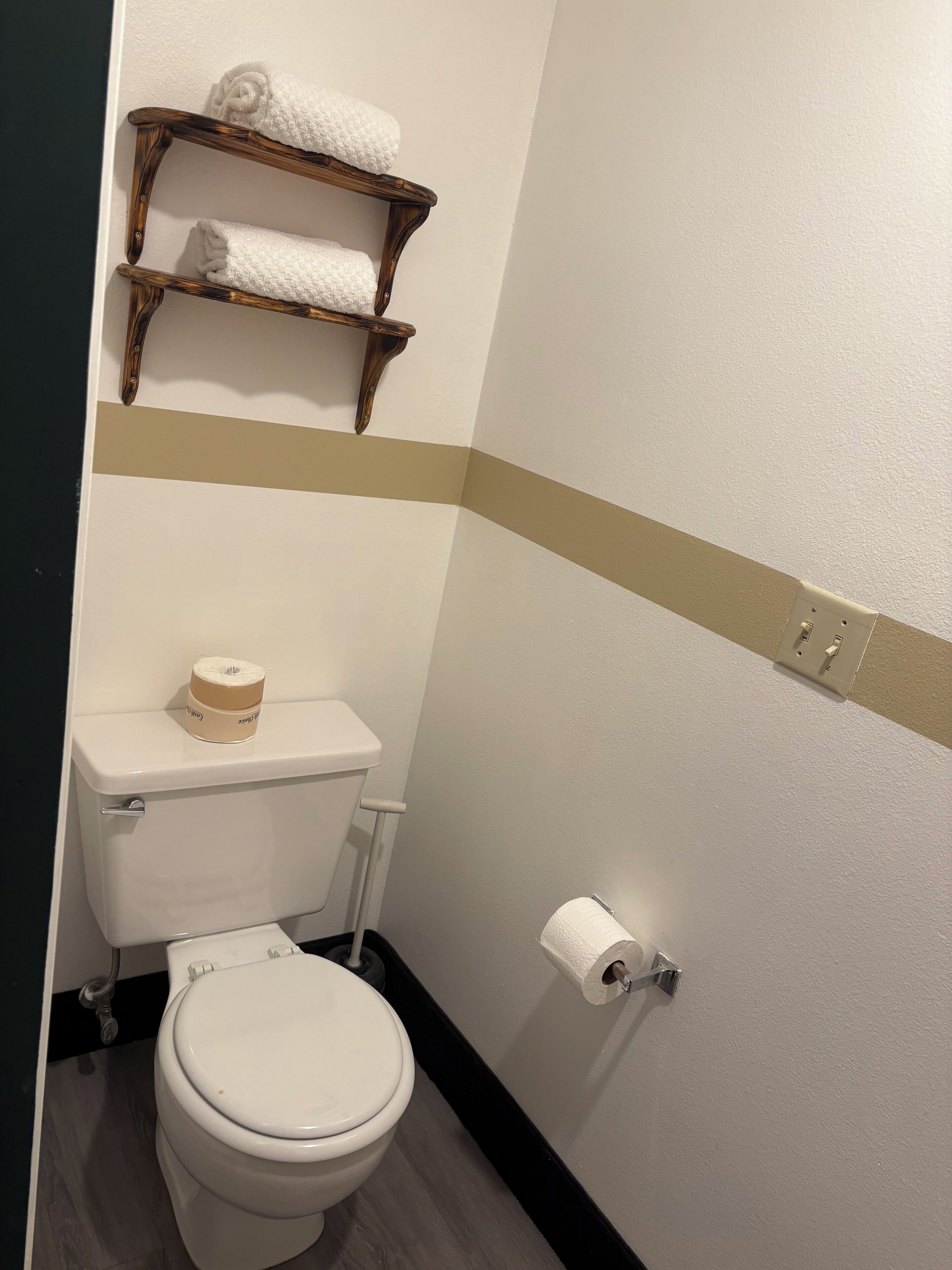 Un bagno piccolo con il water, uno scaffale con asciugamani e un porta carta igienica.