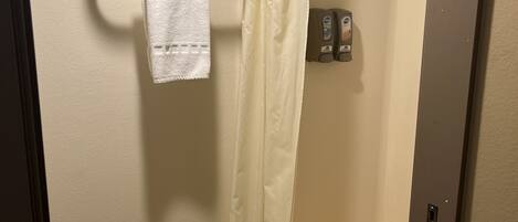 A bathroom with a bathtub, a shower curtain, and a towel rack with a white towel.