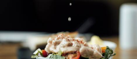 A hand squeezing a lemon over a salad.