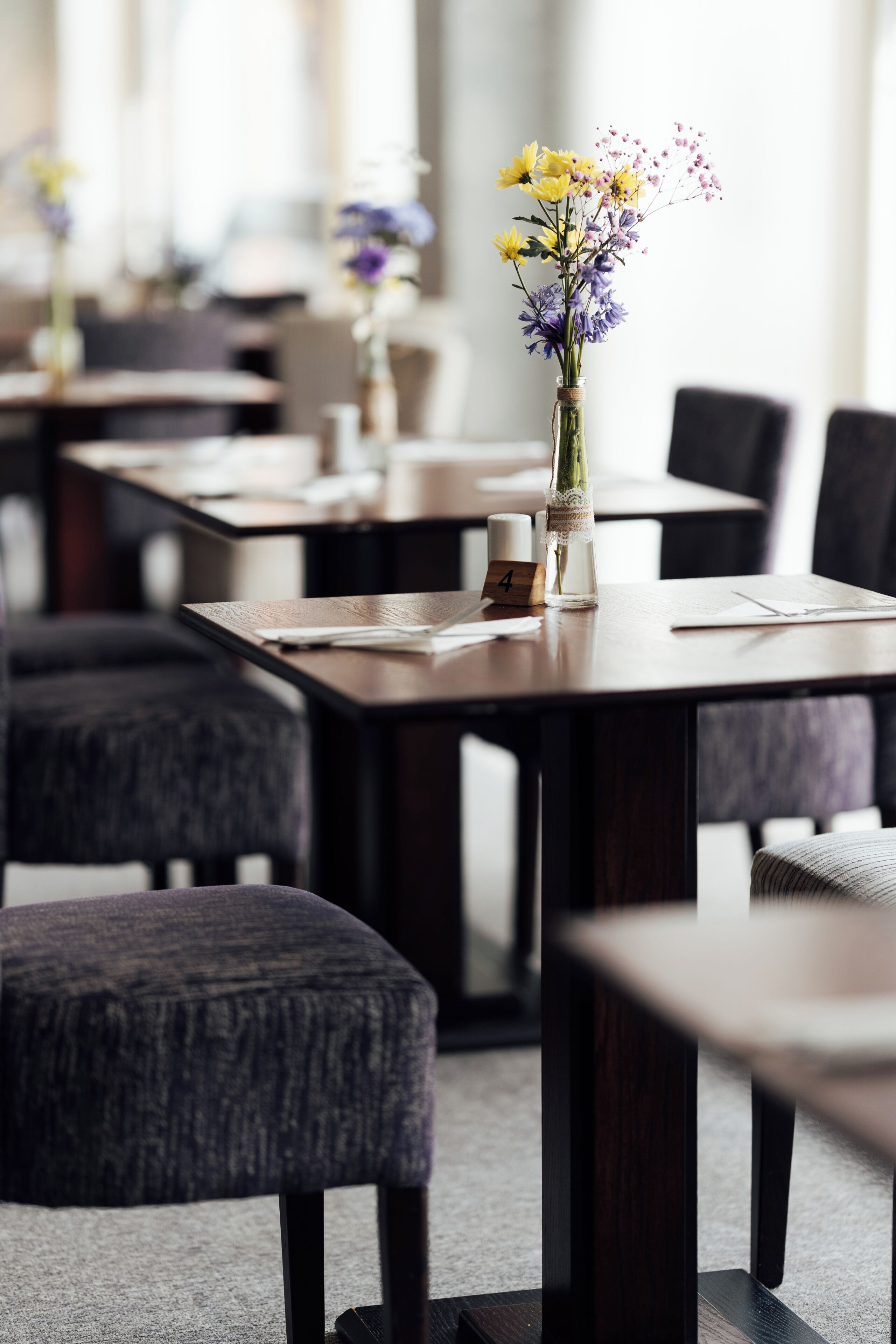 A conference room with tables, chairs, and a vase with flowers.