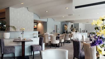 Un vestíbulo de hotel con mostrador de recepción, zona de estar y vistas al comedor.