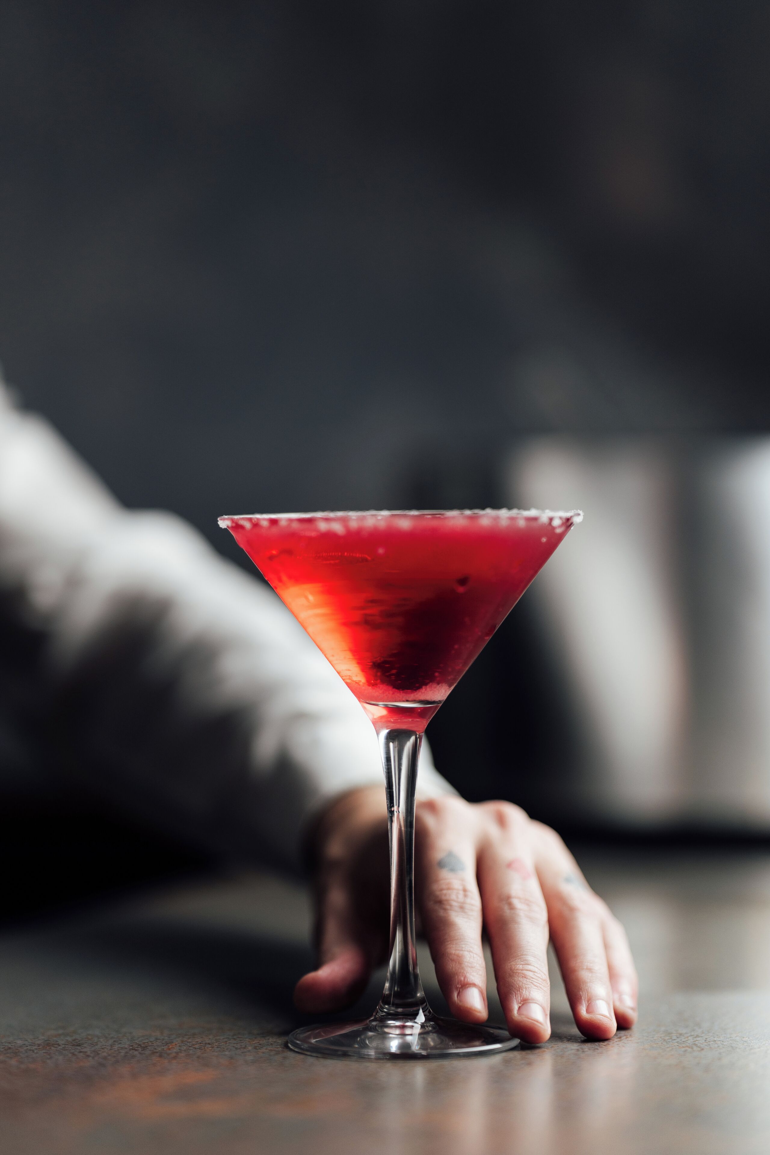 Een martini glas met een rode vloeistof op een tafel.