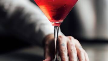 Una copa de martini con una bebida roja sobre una mesa.