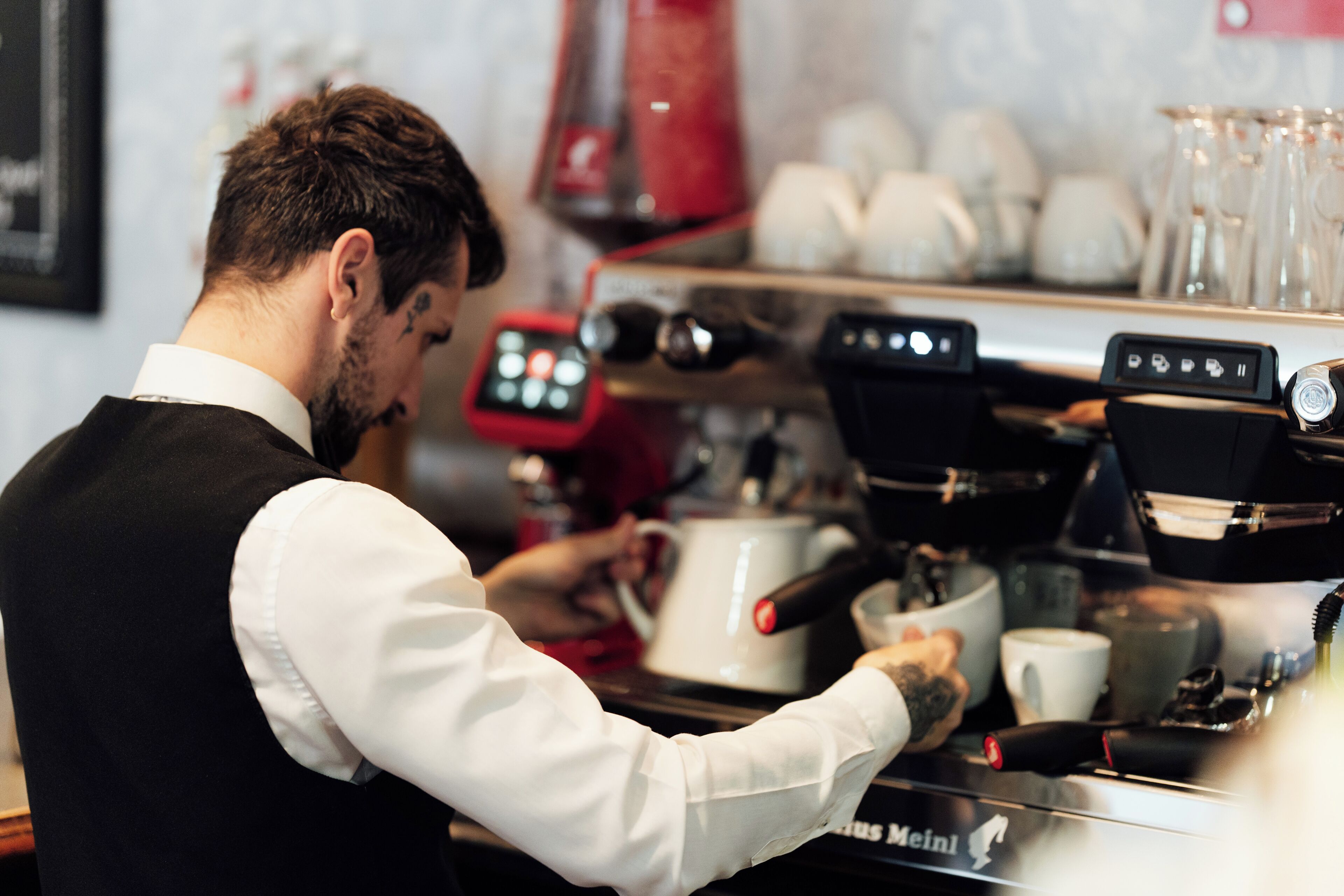 Un barista au travail, utilisant une machine à expresso dotée d’un écran numérique.