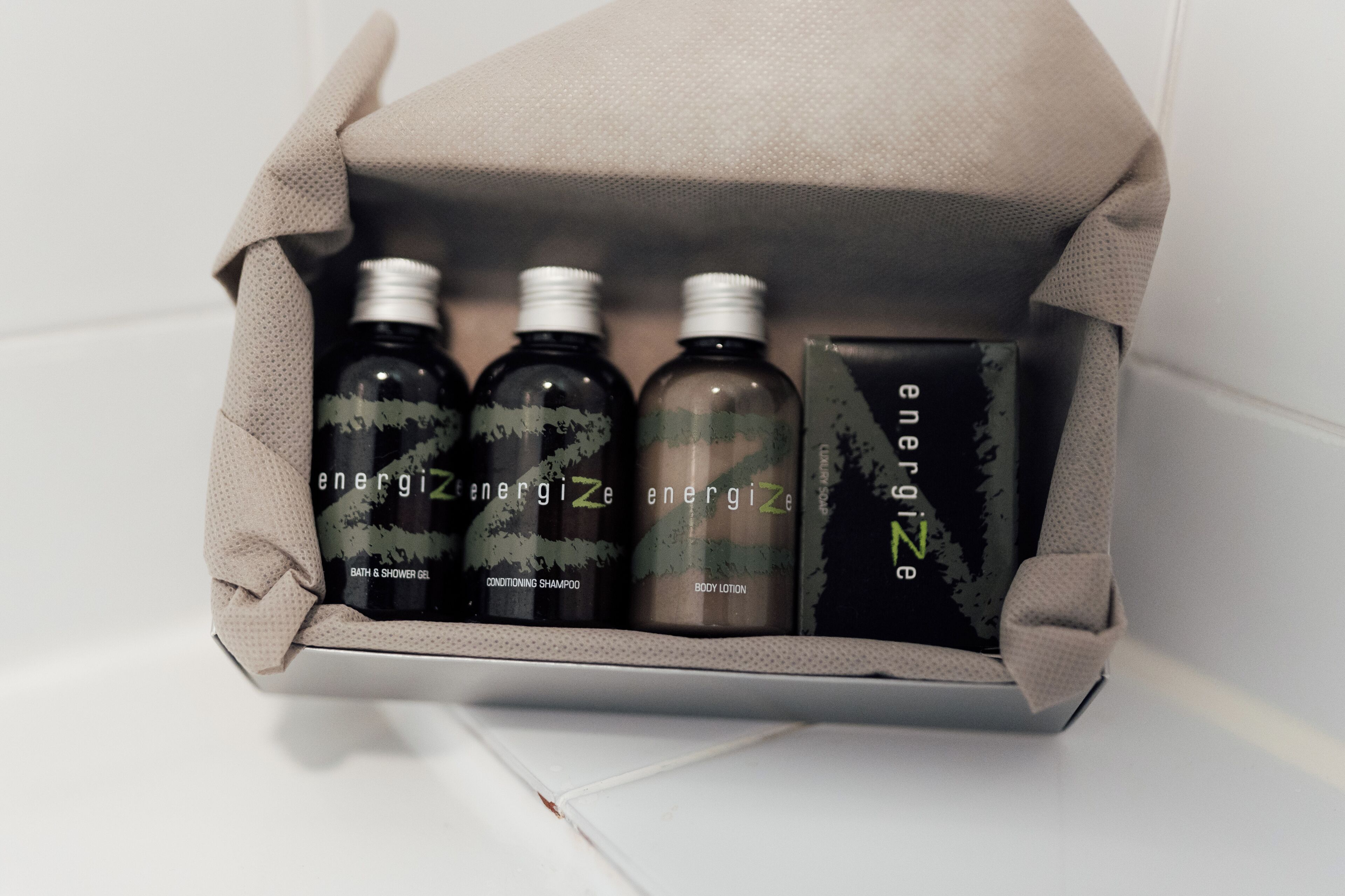 A set of three bottles and a box, likely containing bath and body products, in a neutral-colored packaging.