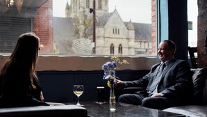 A man and a woman sitting at a table with a vase of flowers, a glass of wine, and a beer mug. - Corus St James Hotel Grimsby (Grimsby)