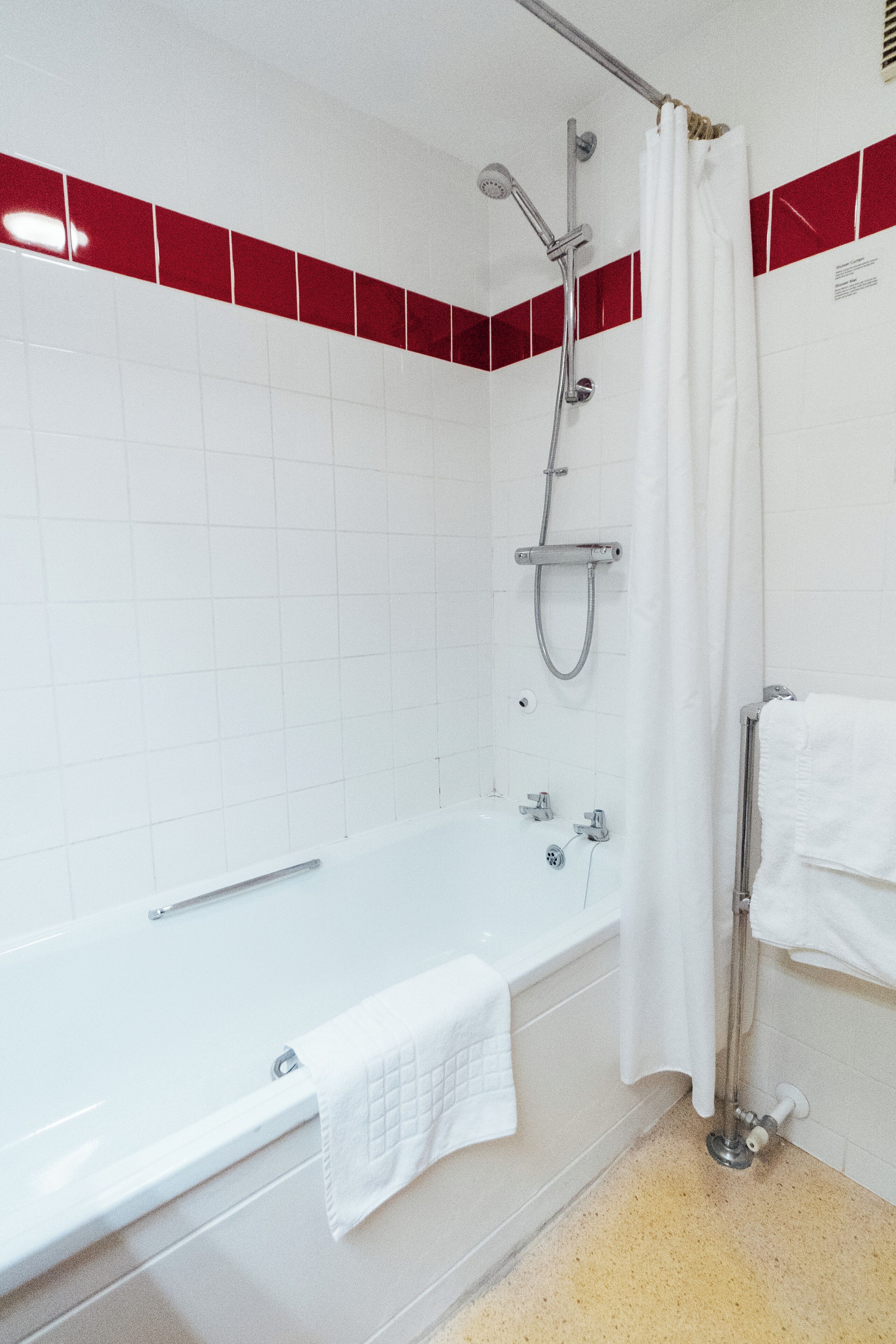 A modern bathroom with a white bathtub, a showerhead, and a towel rack.