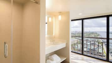 Un baño moderno con un ventanal grande, ducha y tocador con espejo y dos lavamanos.