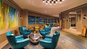 A modern hotel lobby with teal leather chairs, a central round table, and a large abstract painting on the left wall. - Westin Tampa Downtown Waterside (Tampa)