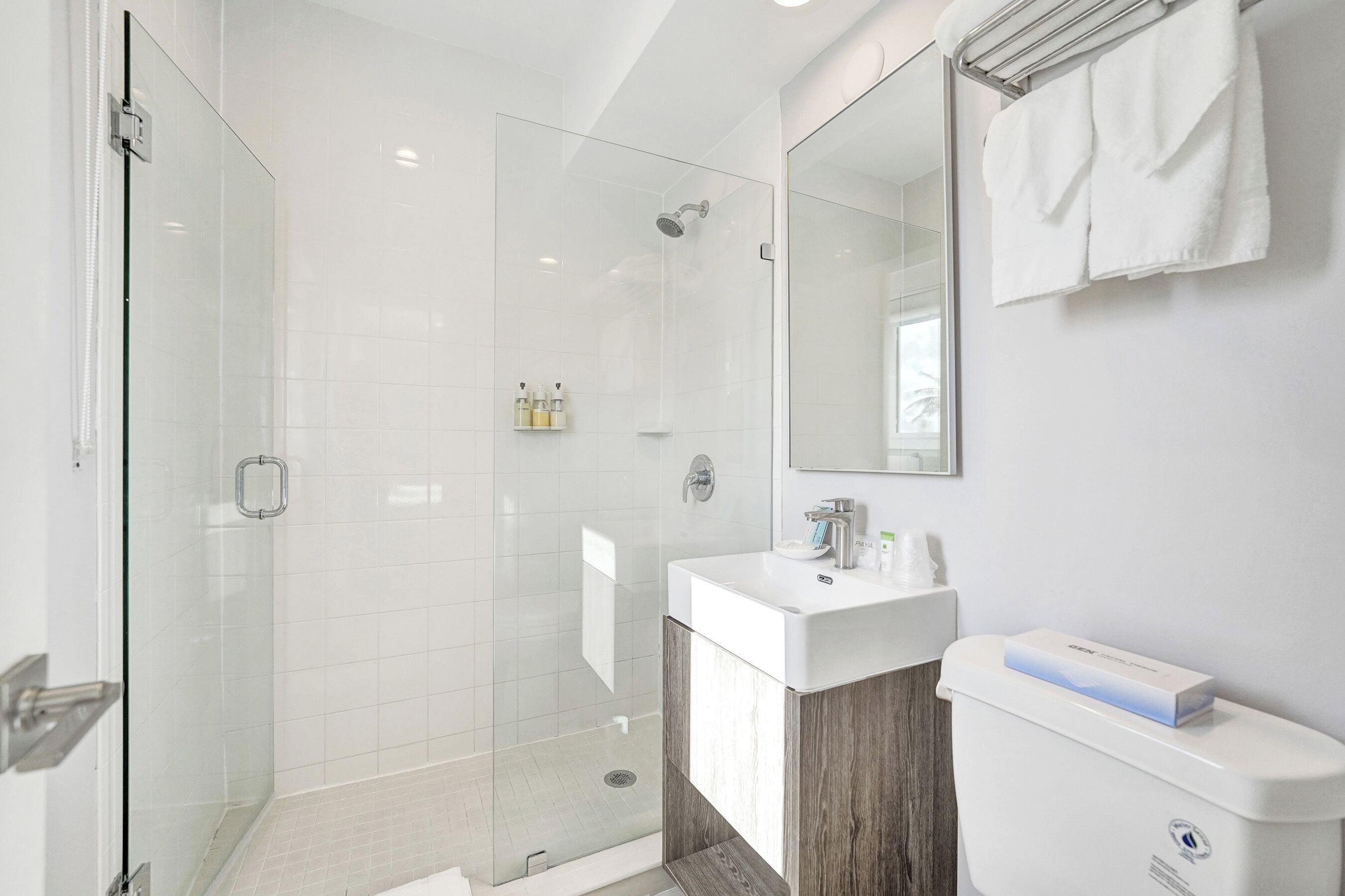 A modern bathroom with a glass-enclosed shower, a white sink, and a large mirror.