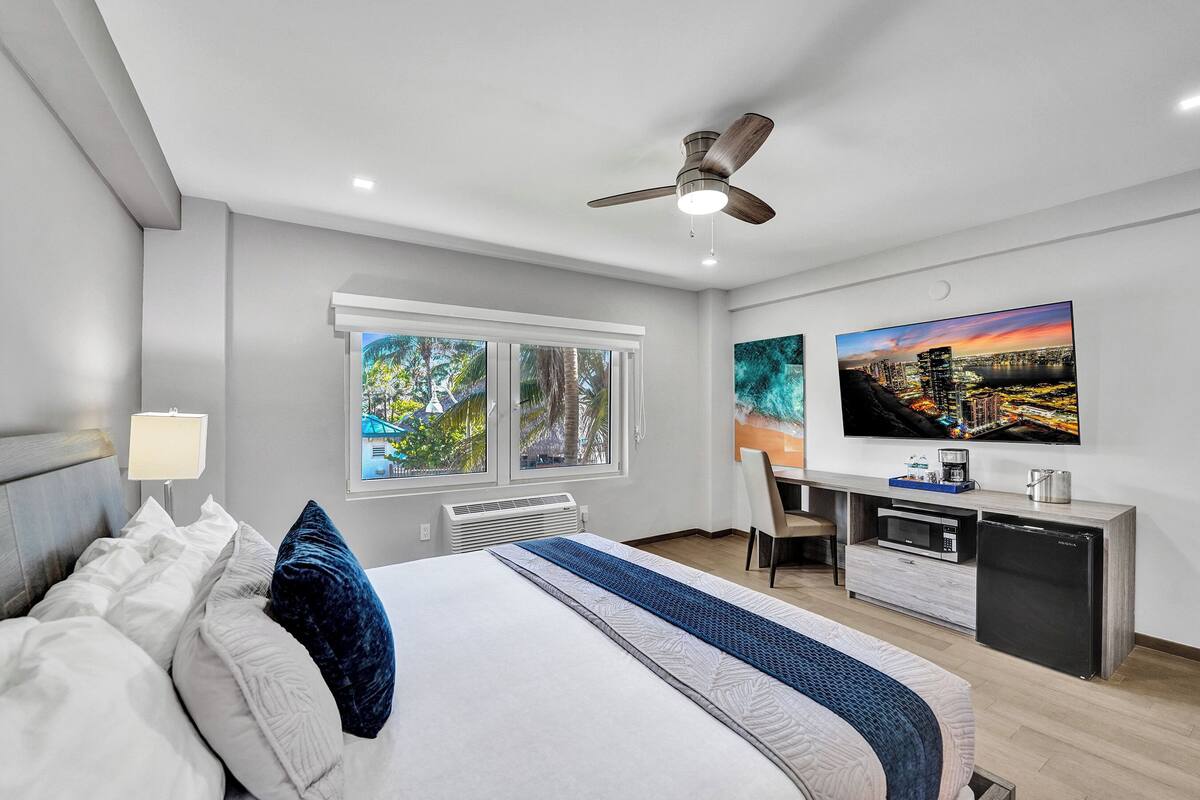 A modern hotel room with a bed, desk, and seating area.