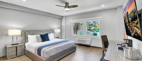 A modern bedroom with a bed, bedside tables, a desk, and a ceiling fan.