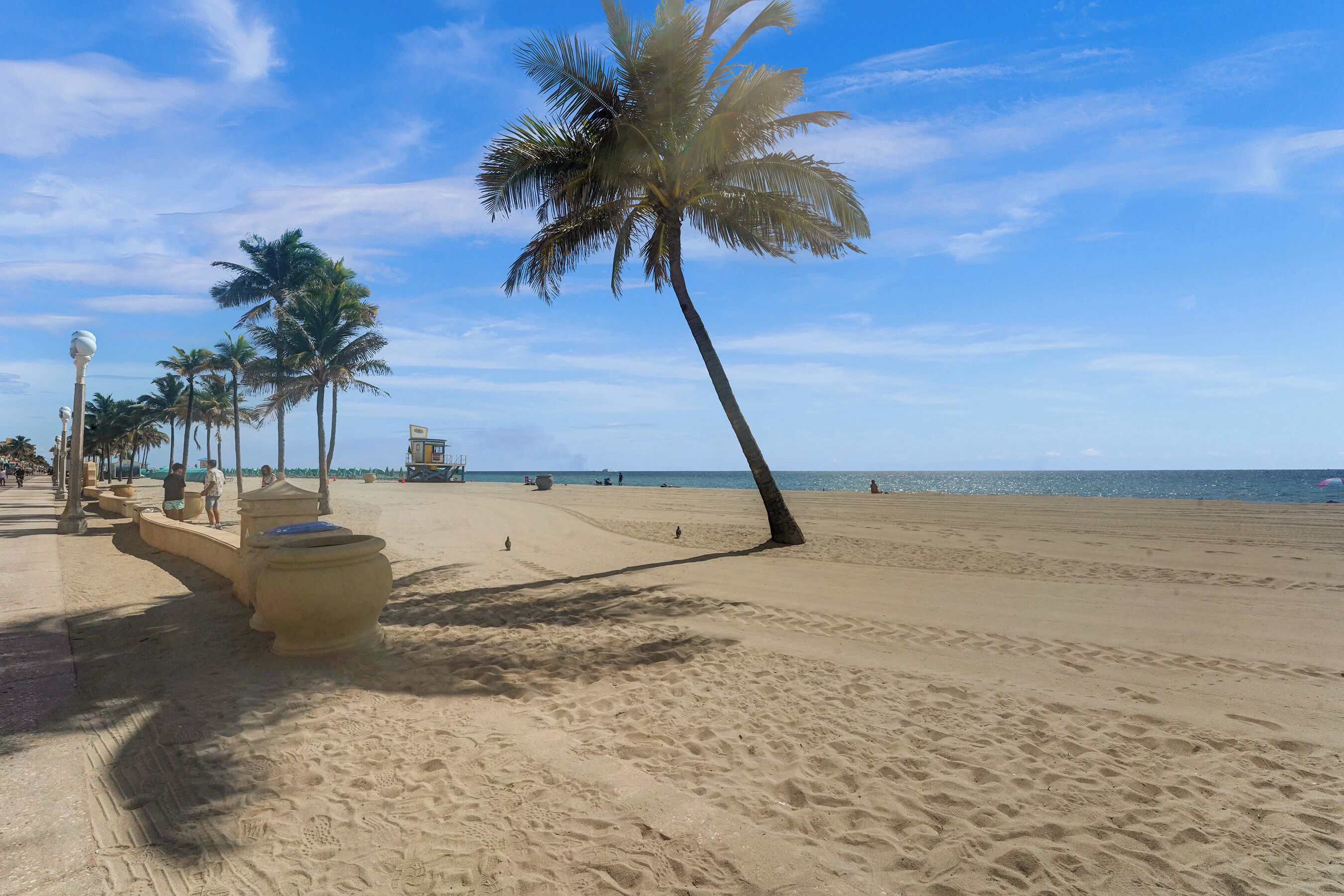 Ein Sandstrand mit Palmen und blauem Himmel.