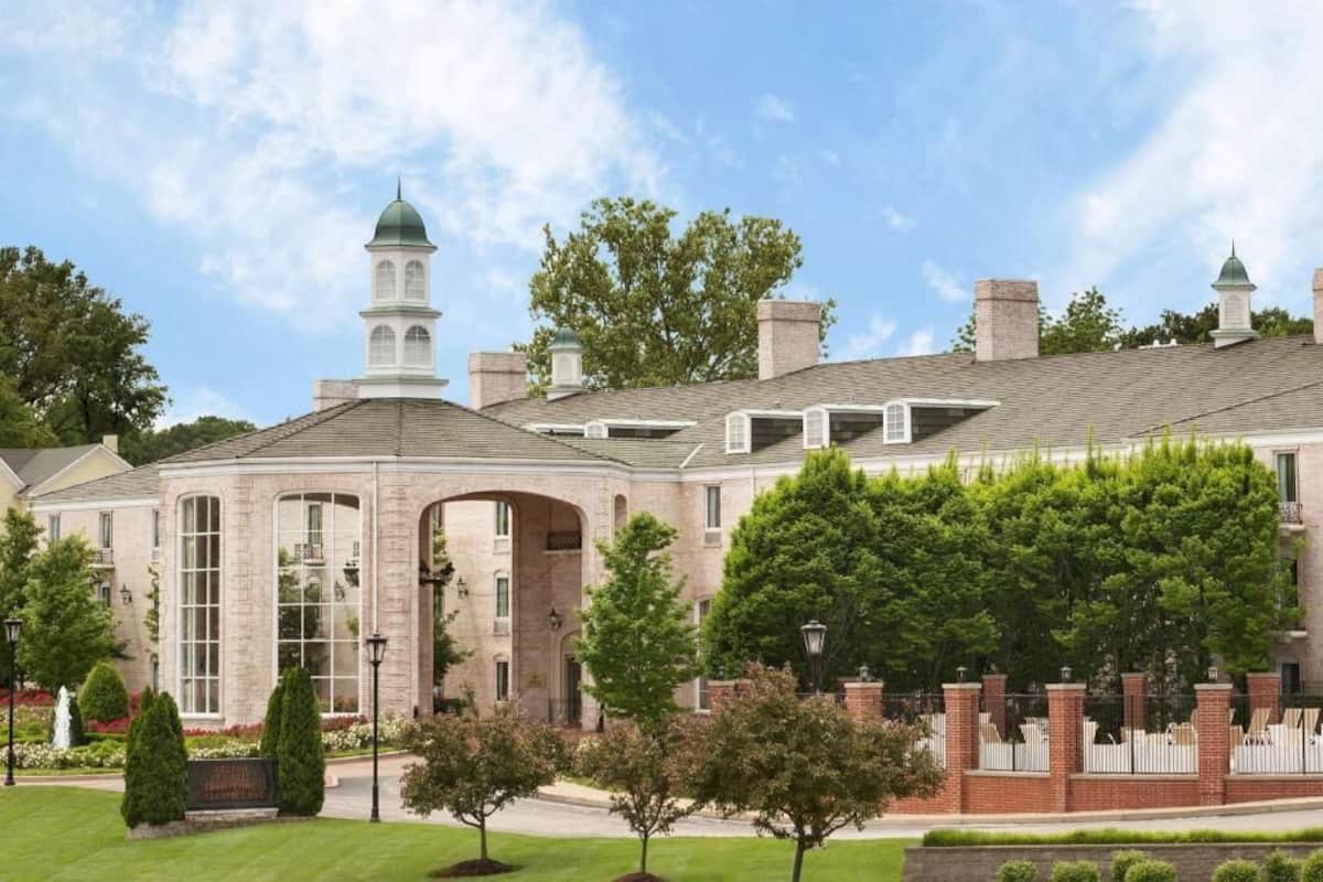 A large brick building with a central dome and arched windows, surrounded by well-maintained lawns and trees.