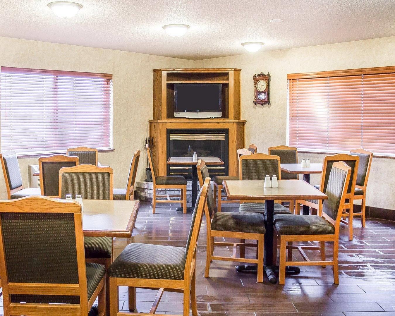A restaurant interior with wooden tables and chairs, a television, and a clock on the wall.