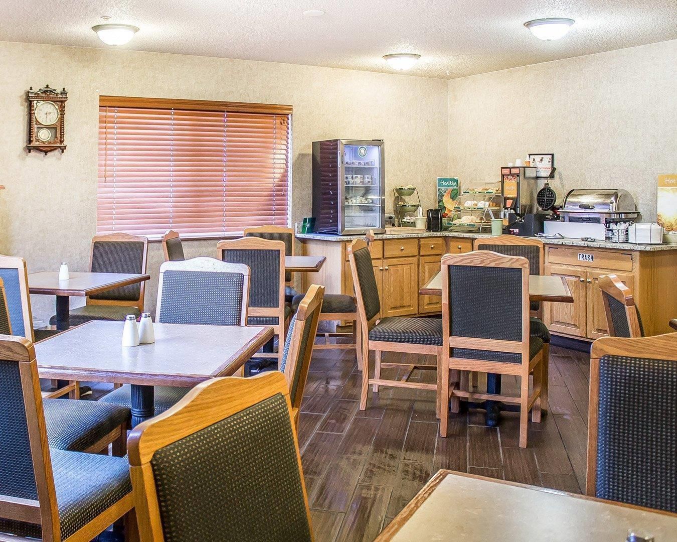 A restaurant with wooden tables and chairs, a refrigerator, and a coffee machine.