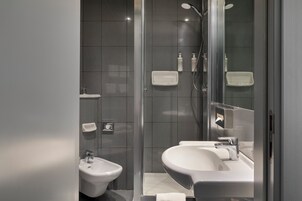 Un bagno moderno con doccia vetrata, un bidet e un lavandino.