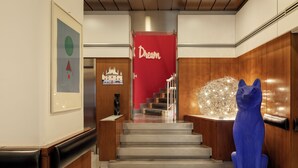 A hotel lobby with a staircase, a red door labeled 'Dream,' and a blue cat sculpture. - Hotel Mediolanum (Milan)