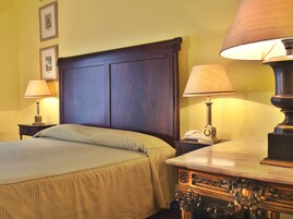 A neatly made bed with a wooden headboard, two bedside lamps, and a nightstand with a telephone.