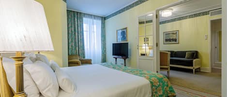 A hotel room with a large bed, a television, a sofa, and a mirror.
