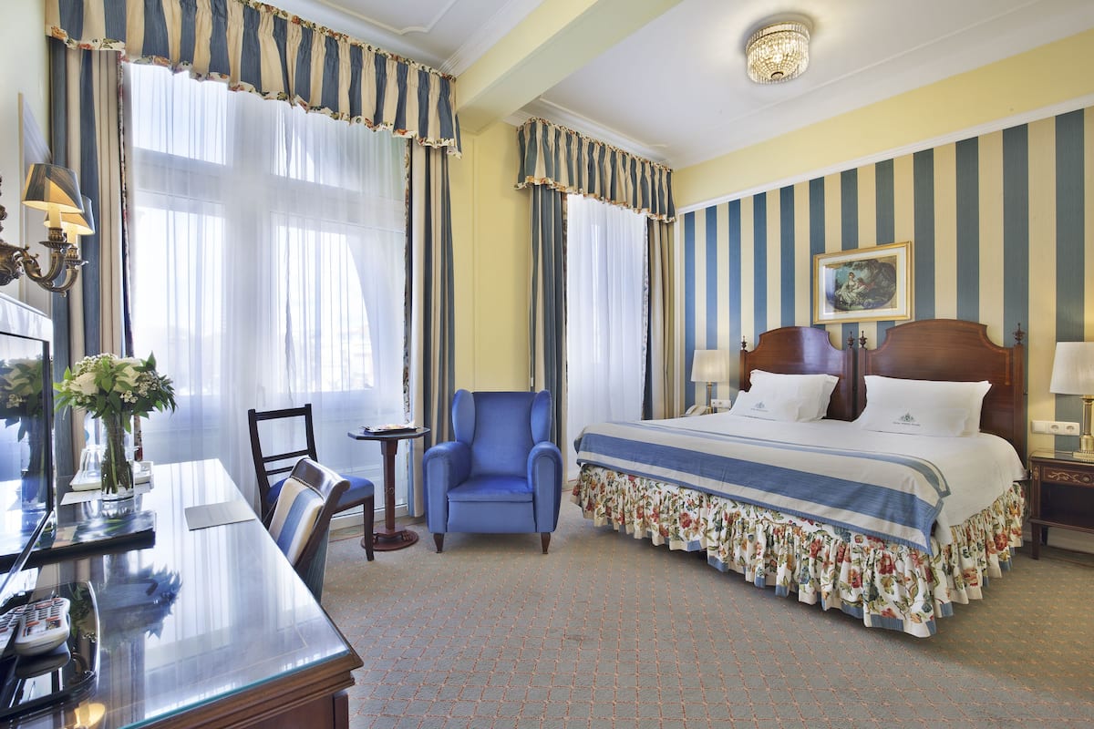 Una camera d'albergo con un letto grande, una scrivania con il telefono, una sedia e un tavolino.
