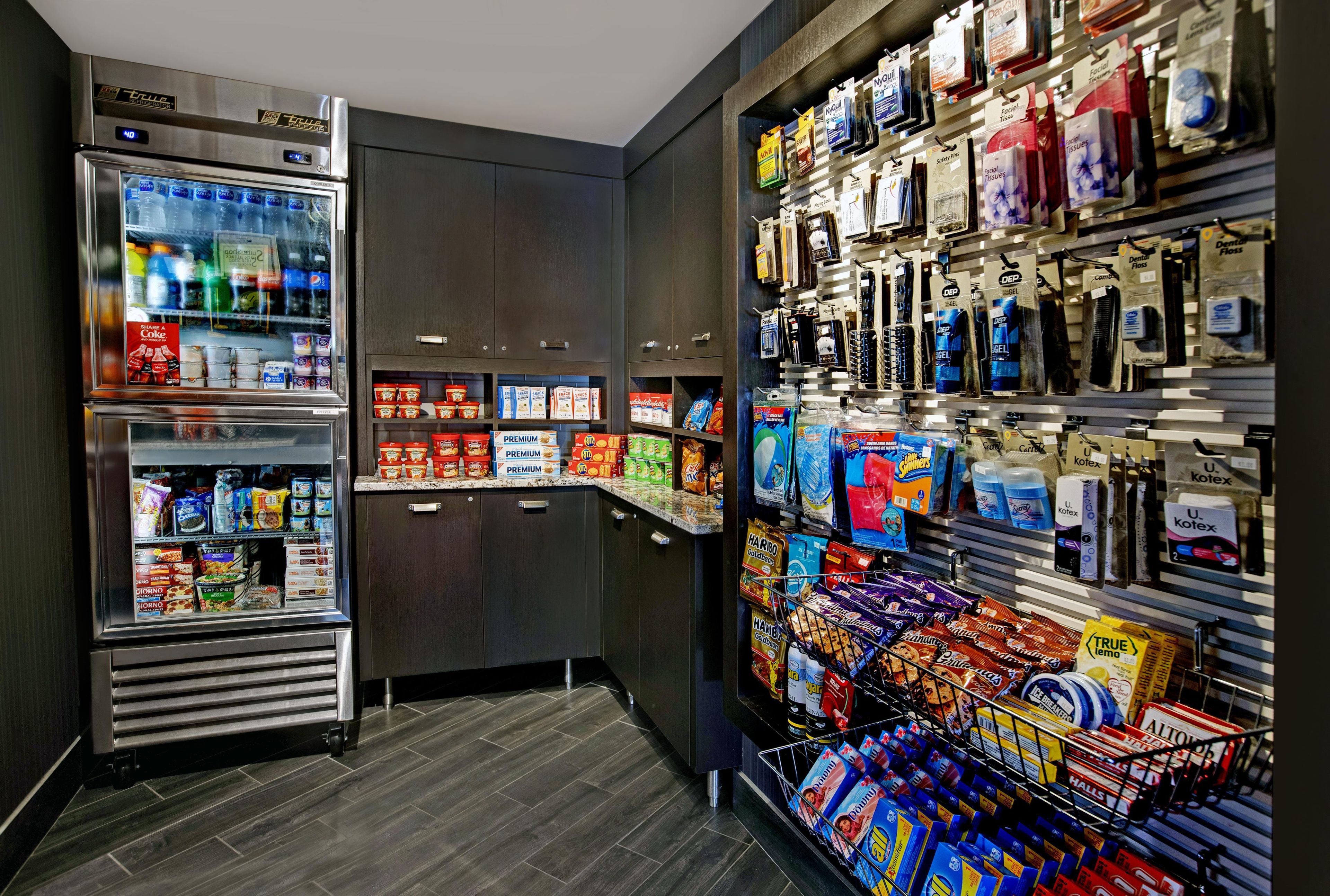 A self-service kiosk with refrigerated beverages and a variety of snacks and personal care items.