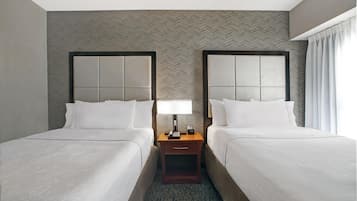 Une chambre d’hôtel avec deux lits, une table de chevet avec une lampe et un mur orné d’un motif en chevrons.