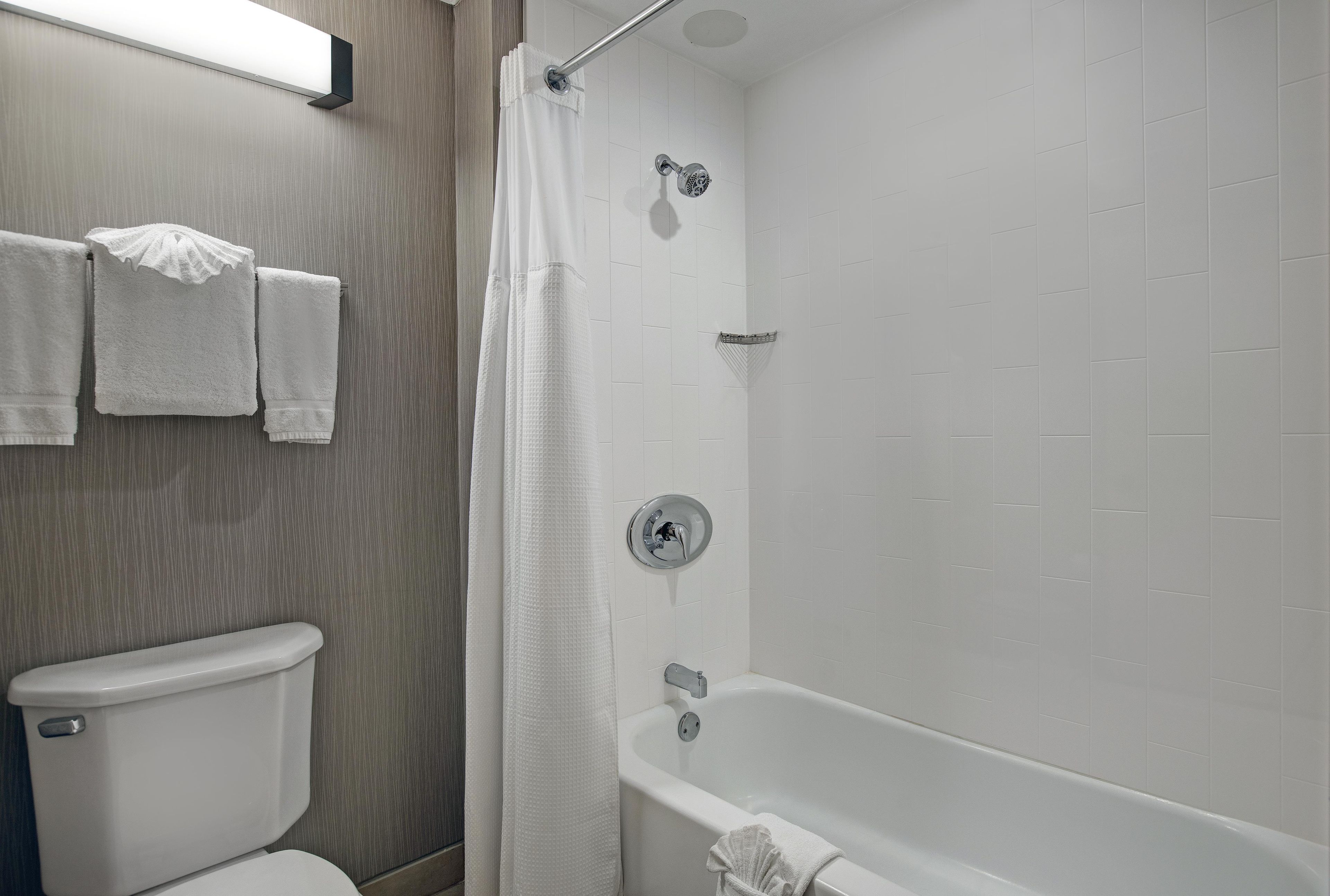 Un baño con inodoro, ducha con puerta de cristal y bañera.