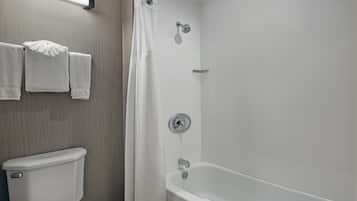 Un baño con inodoro, ducha con puerta de cristal y bañera.