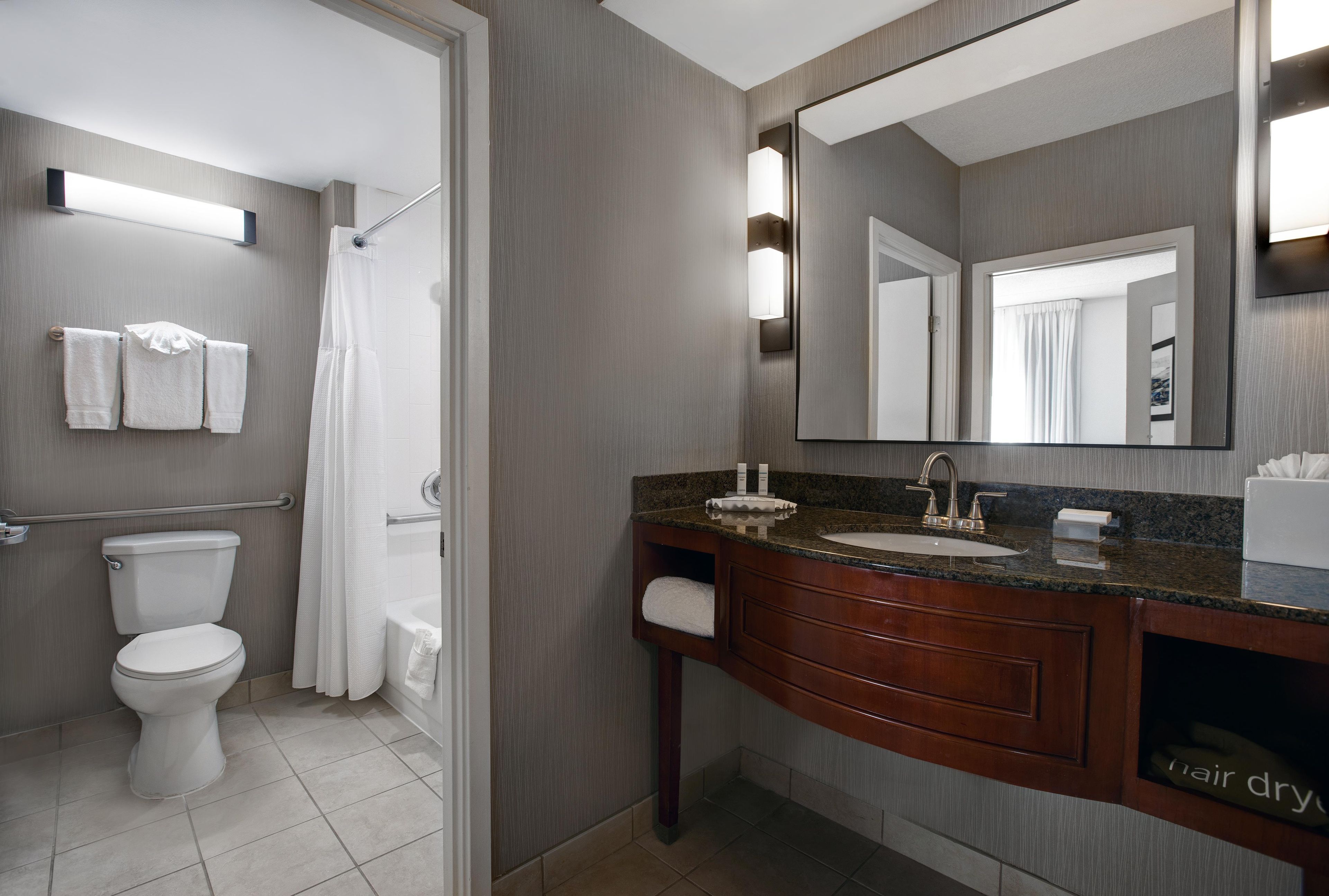 Een moderne badkamer met toilet, douche, wastafel en een grote spiegel.