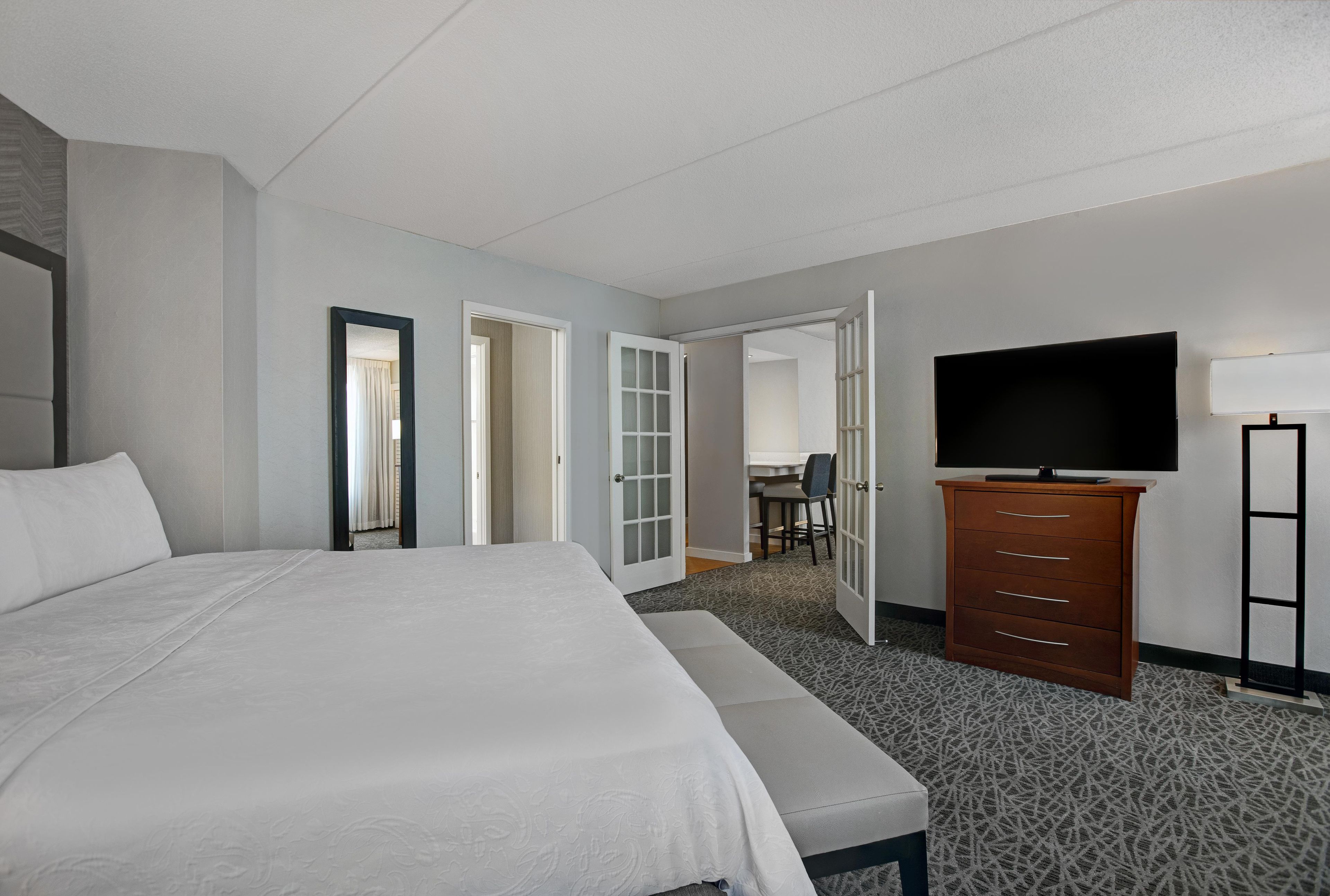 Una habitación de hotel con una cama grande, un aparador, un televisor y un escritorio con una silla.