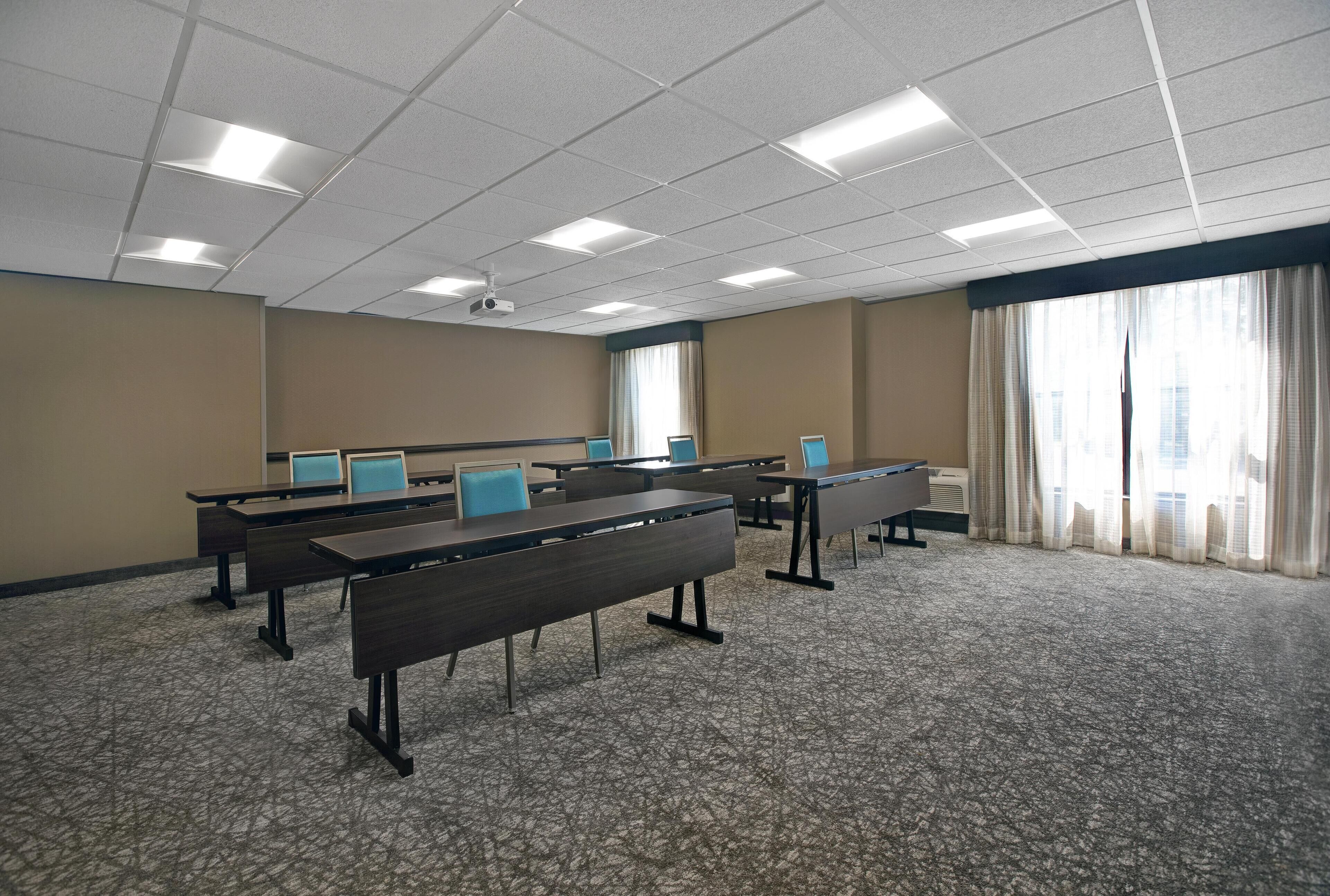 Une salle de conférence équipée de plusieurs tables, de chaises et d’écrans d’ordinateur.