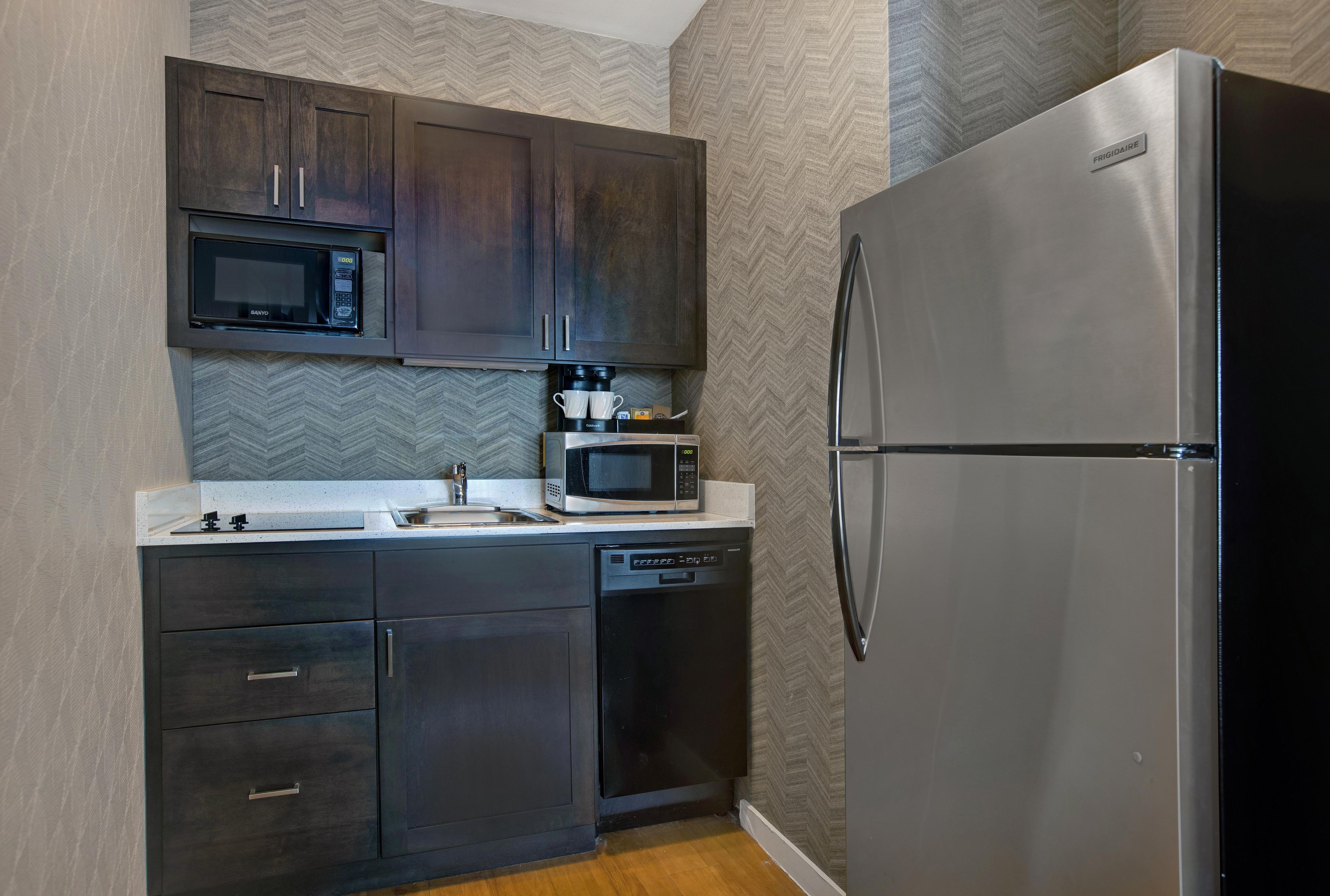 A compact kitchen with a built-in microwave, coffee maker, and dishwasher.