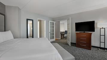 A hotel room with a large bed, a dresser, a TV, and a desk with a chair.
