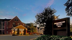Een hotelingang met een bord waarop 'Homewood Suites Hilton' staat.