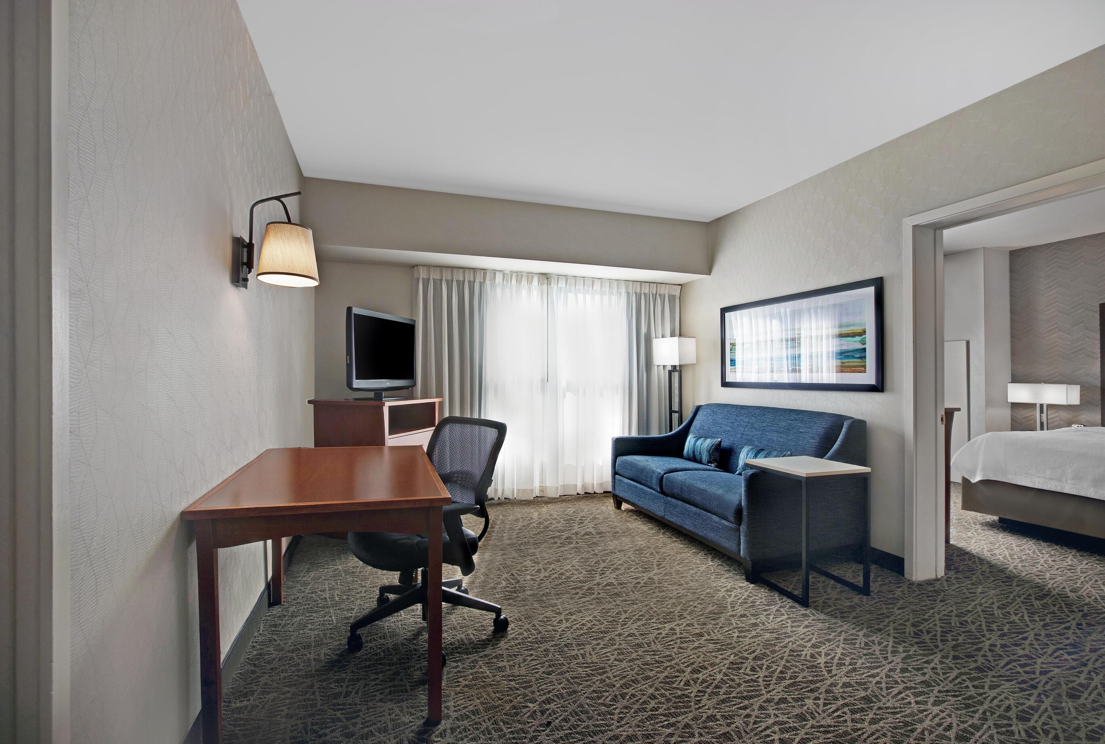 Une chambre d’hôtel équipée d’un bureau, d’une chaise, d’un canapé, d’une télévision et d’un lit.