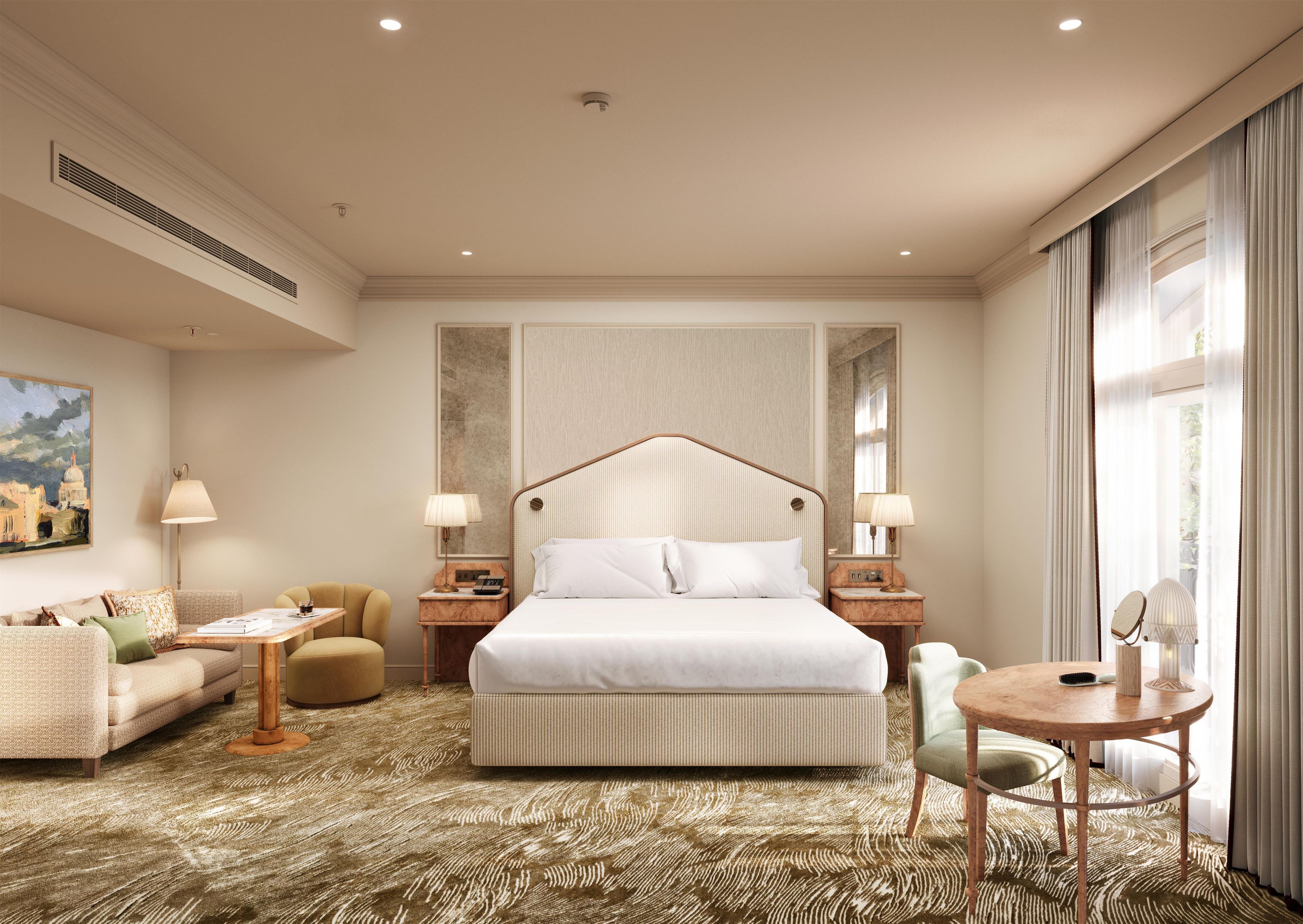 A hotel room with a large bed, a sofa, a small table, and a chair.