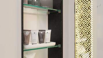 Un bagno con un mobile contenitore nero, uno specchio e mensole con articoli da toilette.