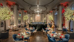 A grand dining room with chandeliers, large windows, and a central bar area. - The Waldorf Hilton, London (London)