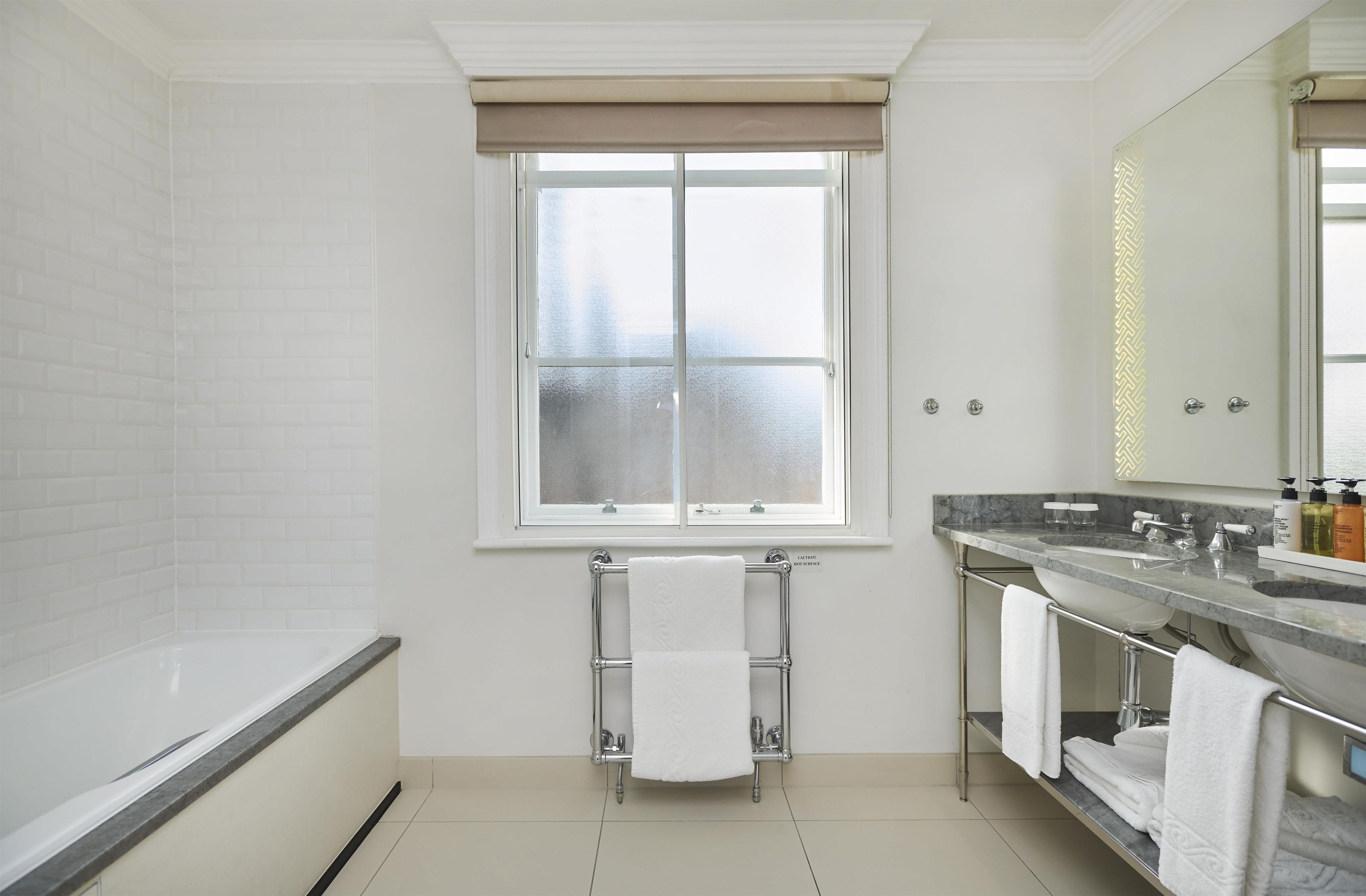 A modern bathroom with a bathtub, a vanity with a sink, and a large mirror.