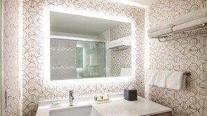 A bathroom with a large mirror, a sink, and a towel rack. - Holiday Inn & Suites Pittsfield-Berkshires by IHG (Pittsfield)