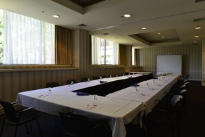 A conference room with a long table, chairs, and a projector screen. - Holiday Inn & Suites Pittsfield-Berkshires by IHG (Pittsfield)