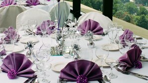 A round dining table set for a formal event, with white tablecloth, silverware, and purple napkins. - Holiday Inn & Suites Pittsfield-Berkshires by IHG (Pittsfield)