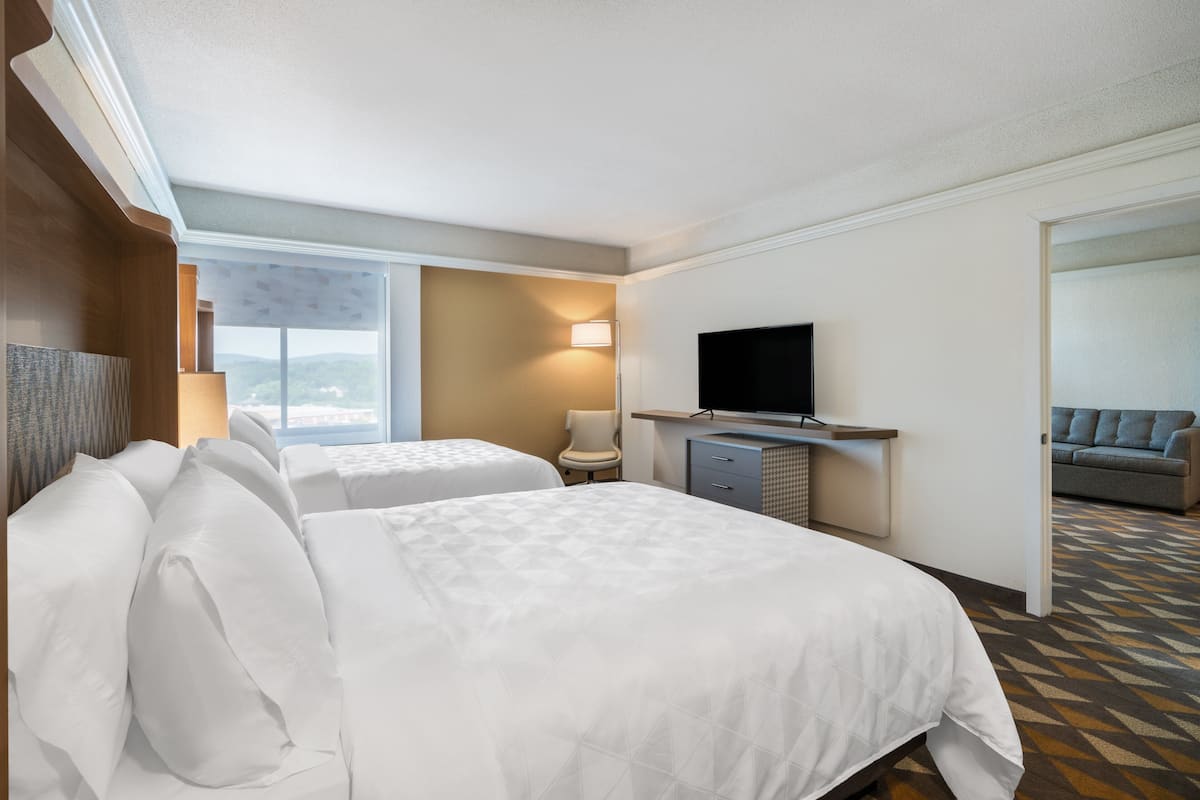 A hotel room with two beds, a TV, a desk, and a chair.