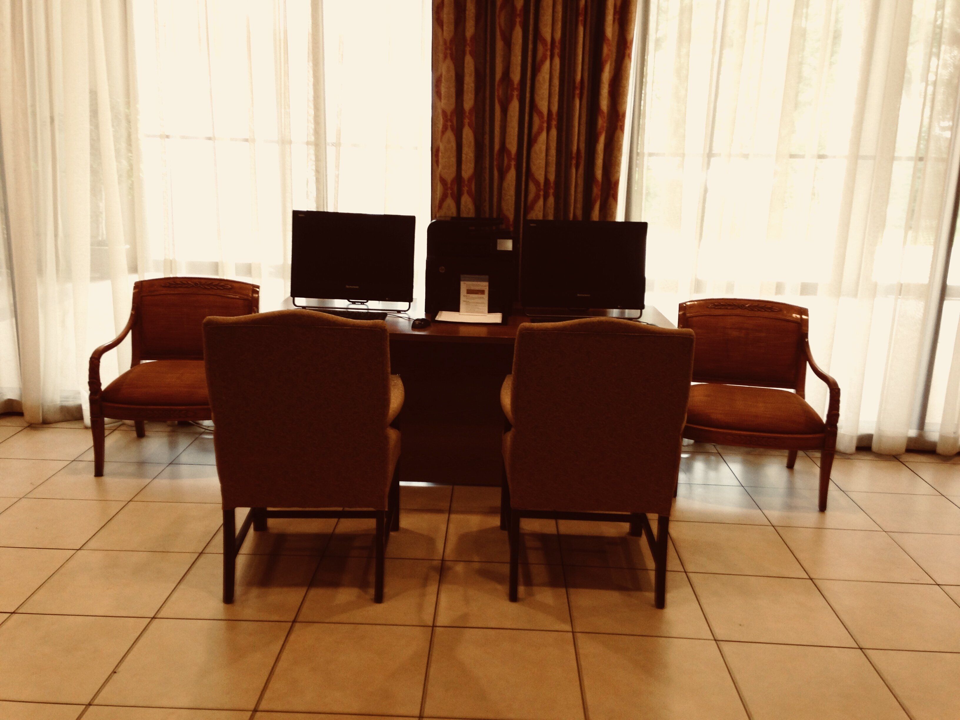 Una habitación con un escritorio, dos monitores y cuatro sillas.