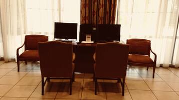 Una habitación con un escritorio, dos monitores y cuatro sillas.