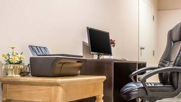 A desk with a printer, a computer monitor, and a chair.