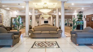A spacious lobby with a central seating area, columns, a chandelier, and potted plants. - Quality Inn & Suites Palm Island Indoor Waterpark (Batavia)